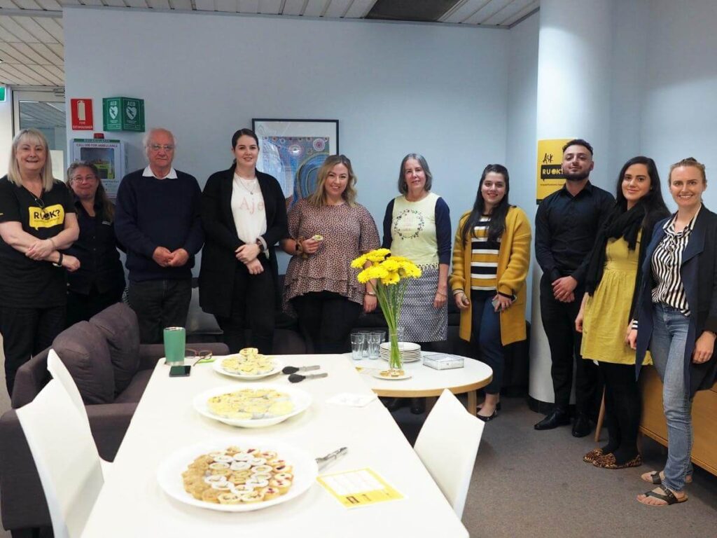 The team celebrating R U OK? Day at the office by interacting together and enjoying tarts
